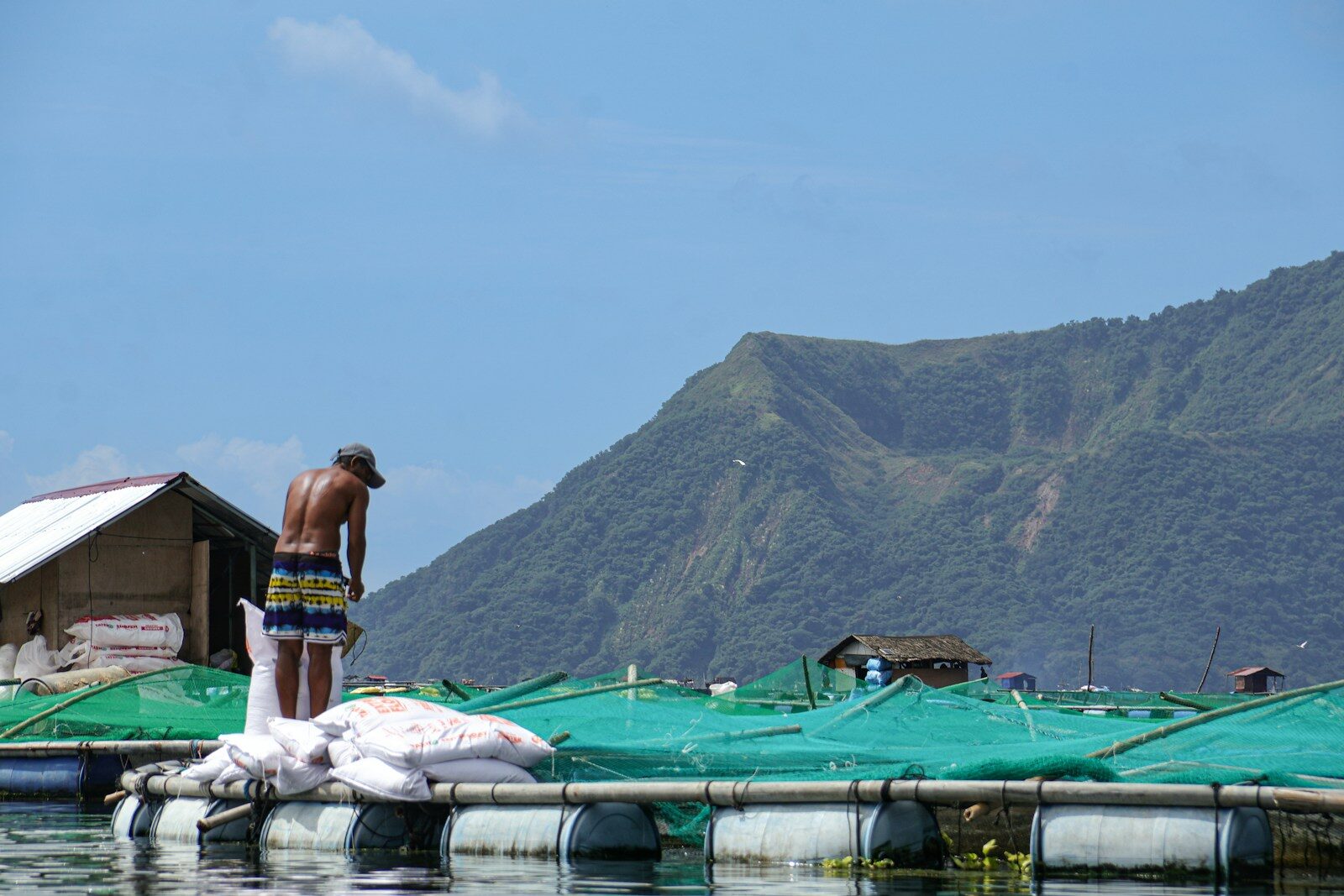 Man on floating structure with mountains behind